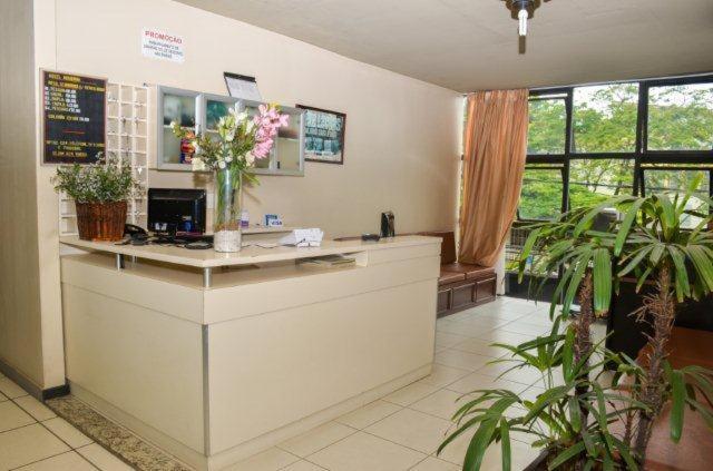 a waiting room with a counter with flowers on it at Hotel Alvorada I in Sete Lagoas