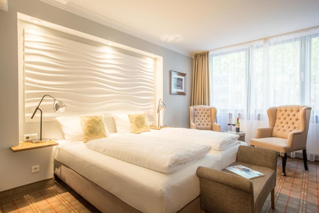 ケルンにあるザ アスコット ホテルのベッドルーム1室(大きな白いベッド1台、椅子2脚付)