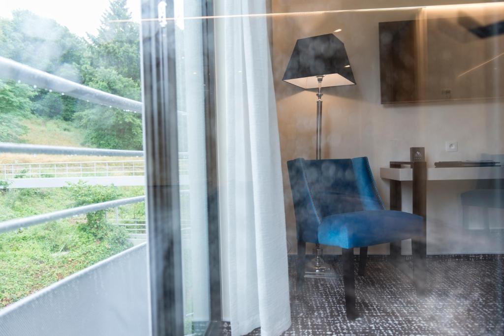 une chaise bleue assise devant un bureau à côté d'une fenêtre dans l'établissement Le Chateau Des Thermes, à Chaudfontaine