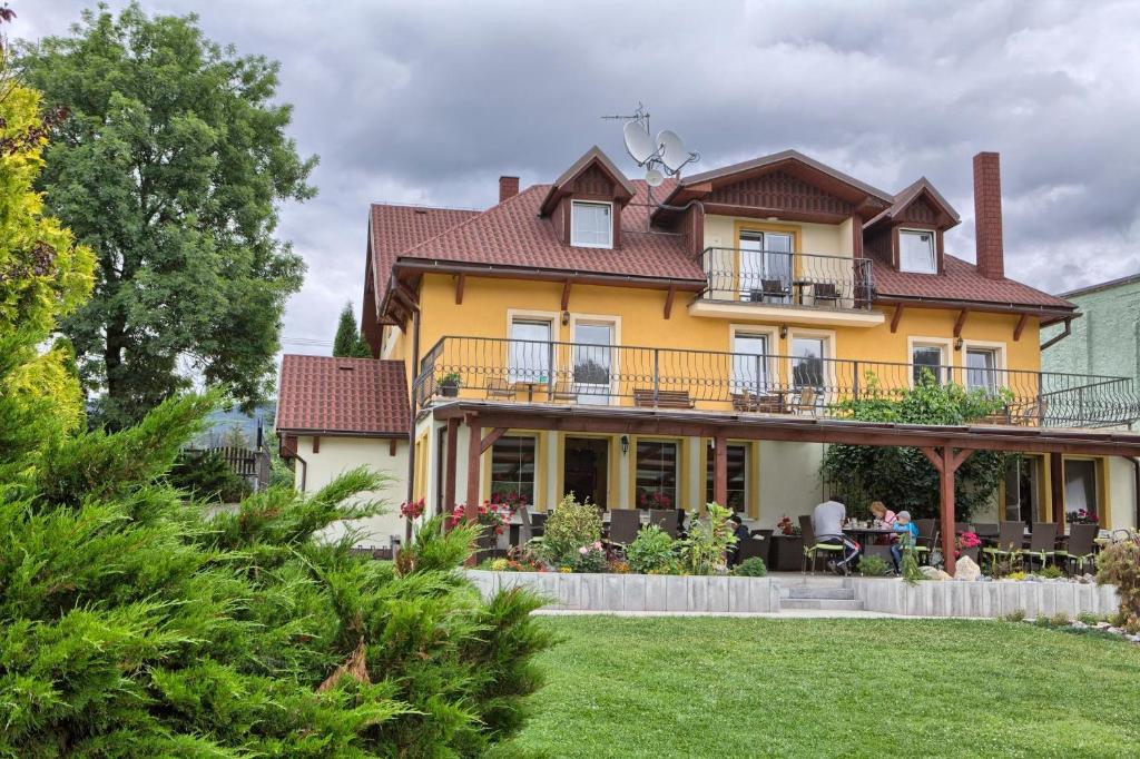 a large yellow house with a balcony at Penzión Fantázia Michalová - Brezno-Muránska planina in Michalová