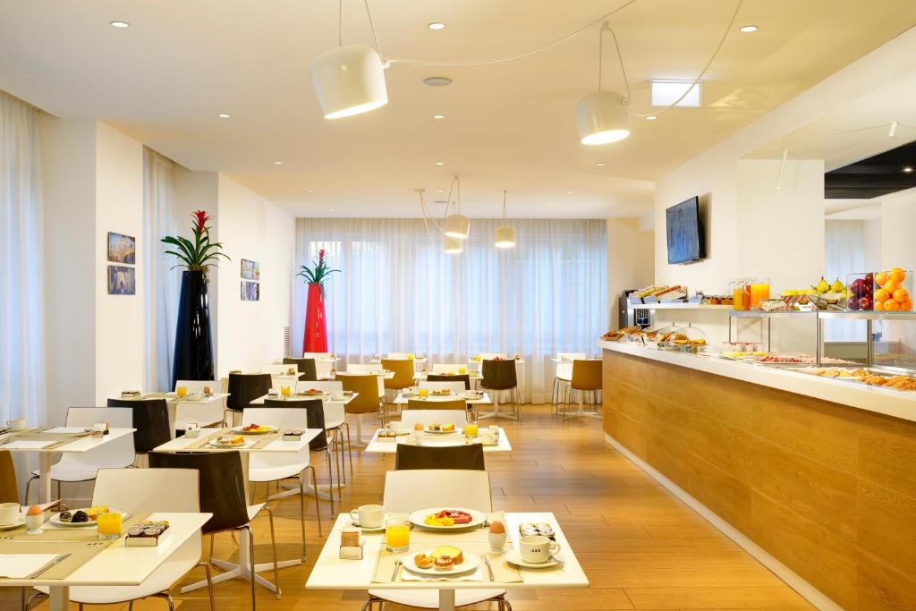 restauracja ze stołami i krzesłami oraz bufetem w obiekcie UNA HOTELS Century Milano w Mediolanie