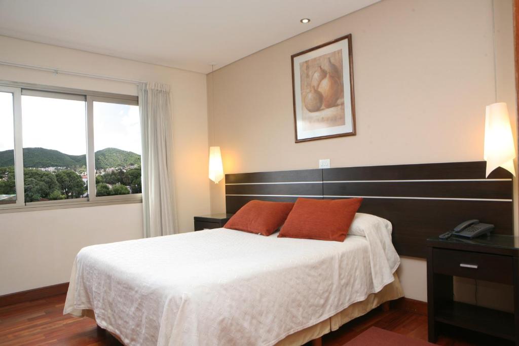 1 dormitorio con 1 cama grande y 2 almohadas de color naranja en Hotel Ankara Suites en Salta