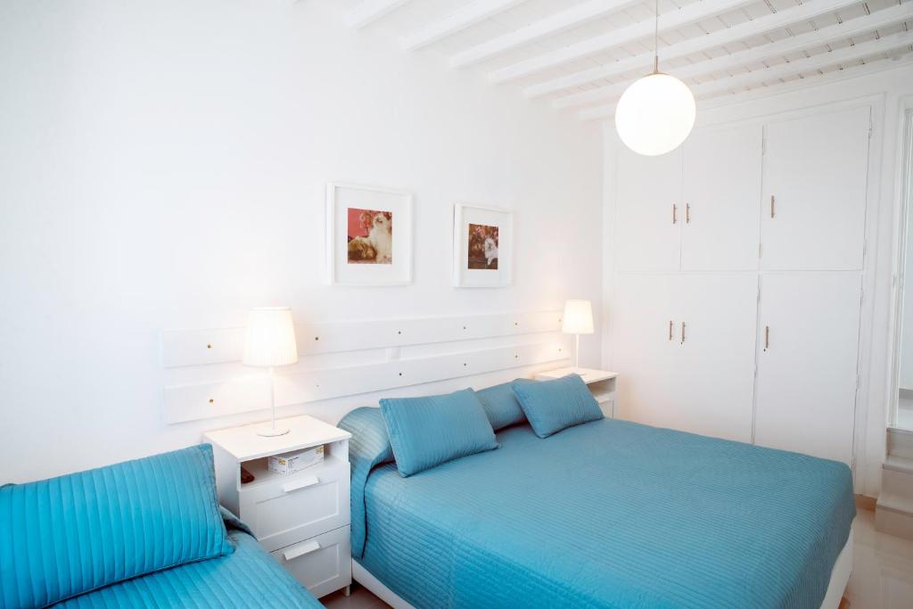 a bedroom with two beds with blue sheets and a table at Chora House in Mýkonos City