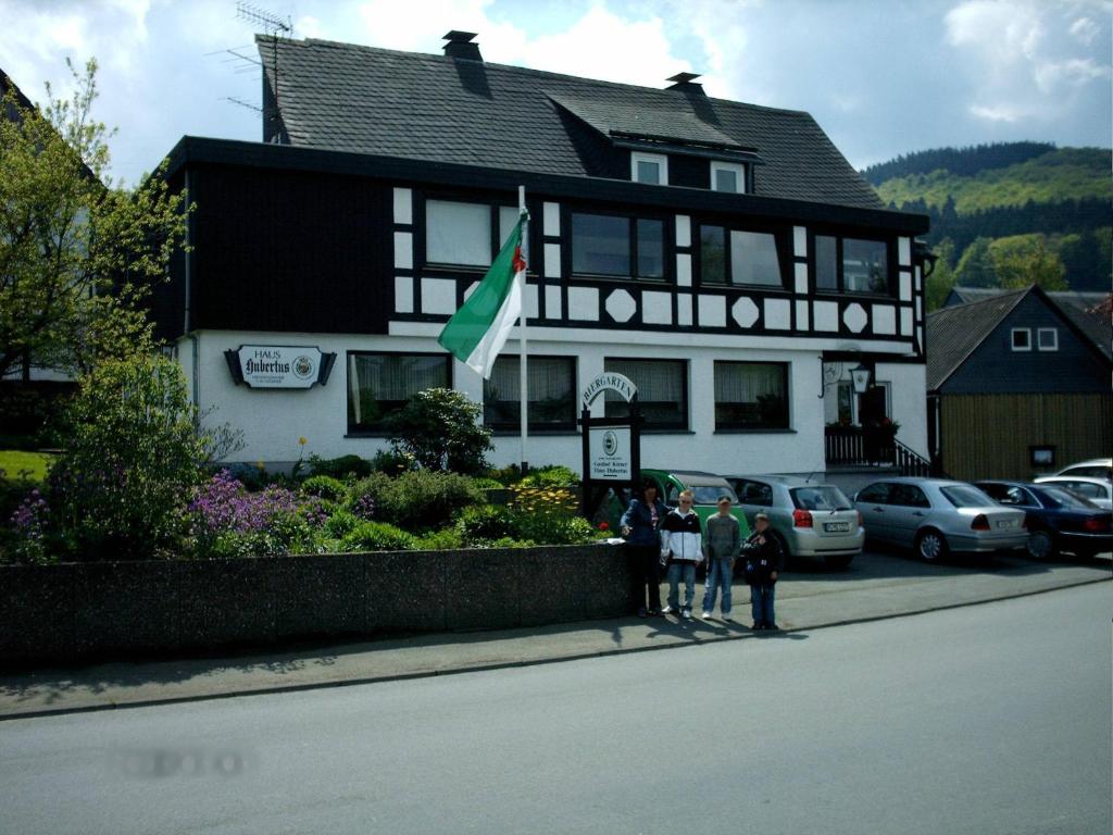 un groupe de personnes debout devant une maison dans l'établissement Gasthof Haus Hubertus, à Winterberg