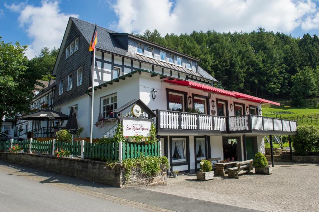 ein großes weißes Gebäude mit einem Zaun davor in der Unterkunft Gasthof Zur Hohen Hunau in Schmallenberg