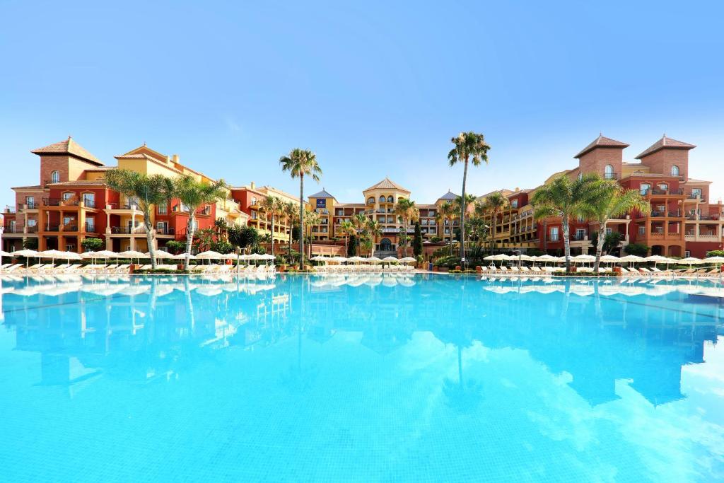 a large swimming pool with palm trees and buildings at Iberostar Málaga Playa in Torrox Costa