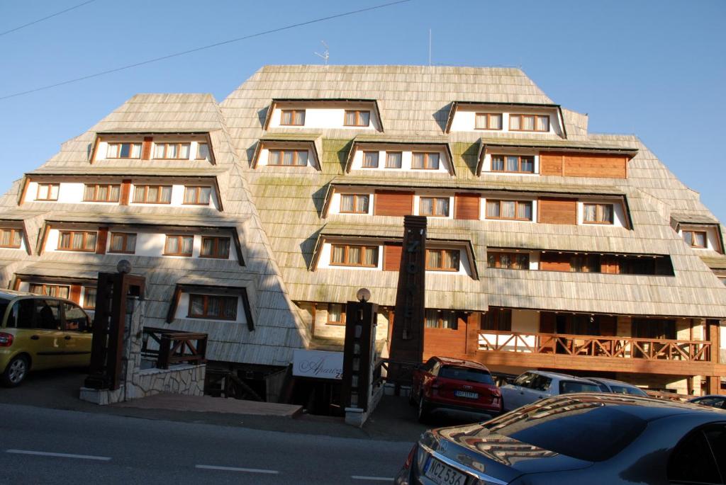 een groot gebouw met auto's geparkeerd voor het bij Apartments Mitic in Kopaonik