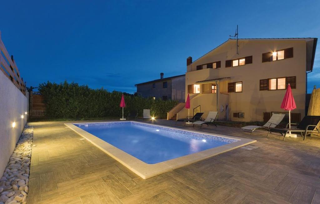 a swimming pool in front of a house at night at Apartments Klaudija in Pula