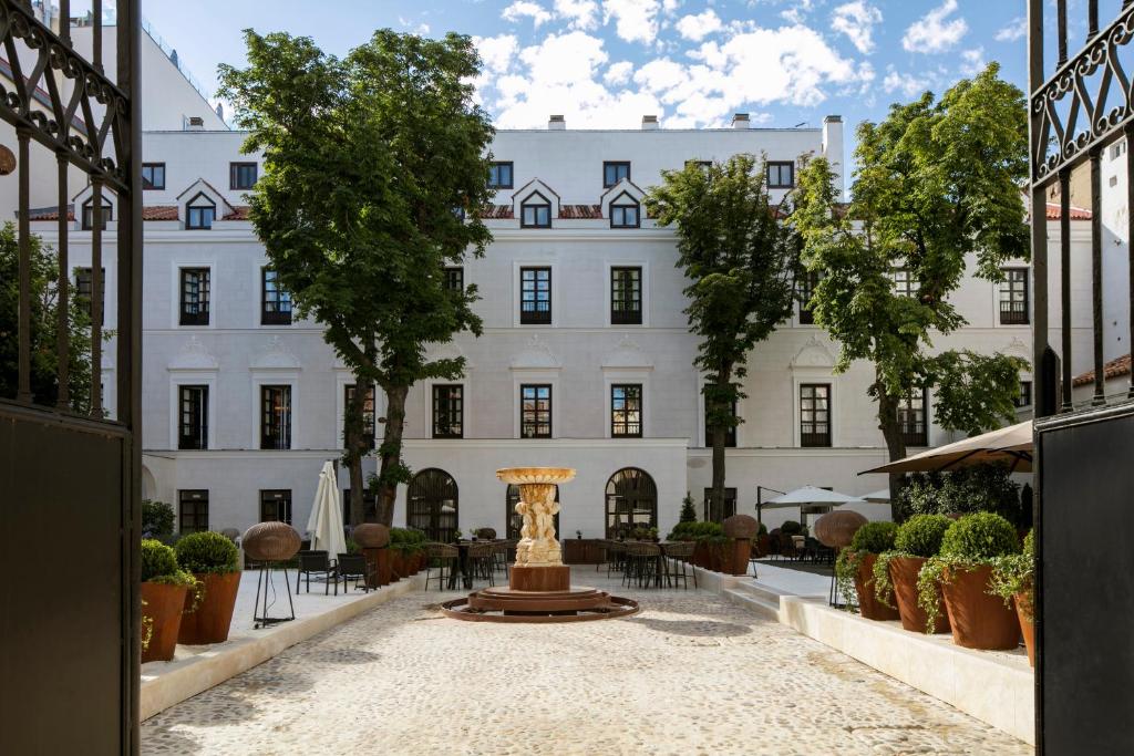 a courtyard with a fountain in front of a white building at Palacio de los Duques Gran Meliá - The Leading Hotels of the World in Madrid