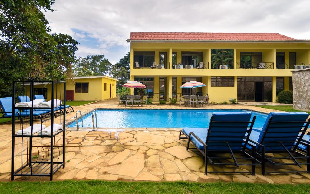 a house with a swimming pool with blue chairs at Mvuli Hotels Arusha in Arusha