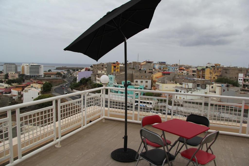a table and chairs on a balcony with an umbrella at Apartamento António in Praia