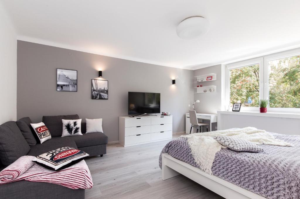 a white bedroom with a bed and a couch at Warsawrent Hit Apartments in Warsaw