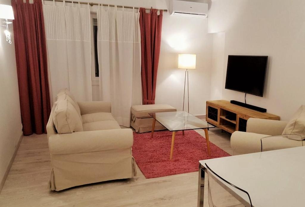 uma sala de estar com mobiliário branco e uma televisão de ecrã plano em Suites Apartments em Cascais