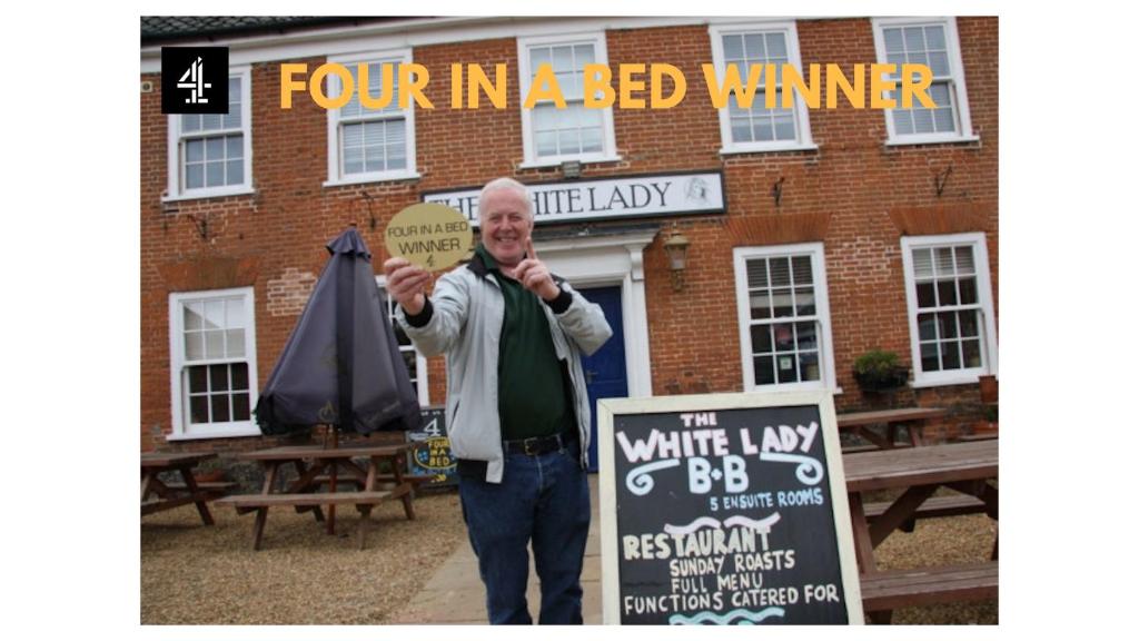 a man holding a sign in front of a building at The White Lady in Worstead