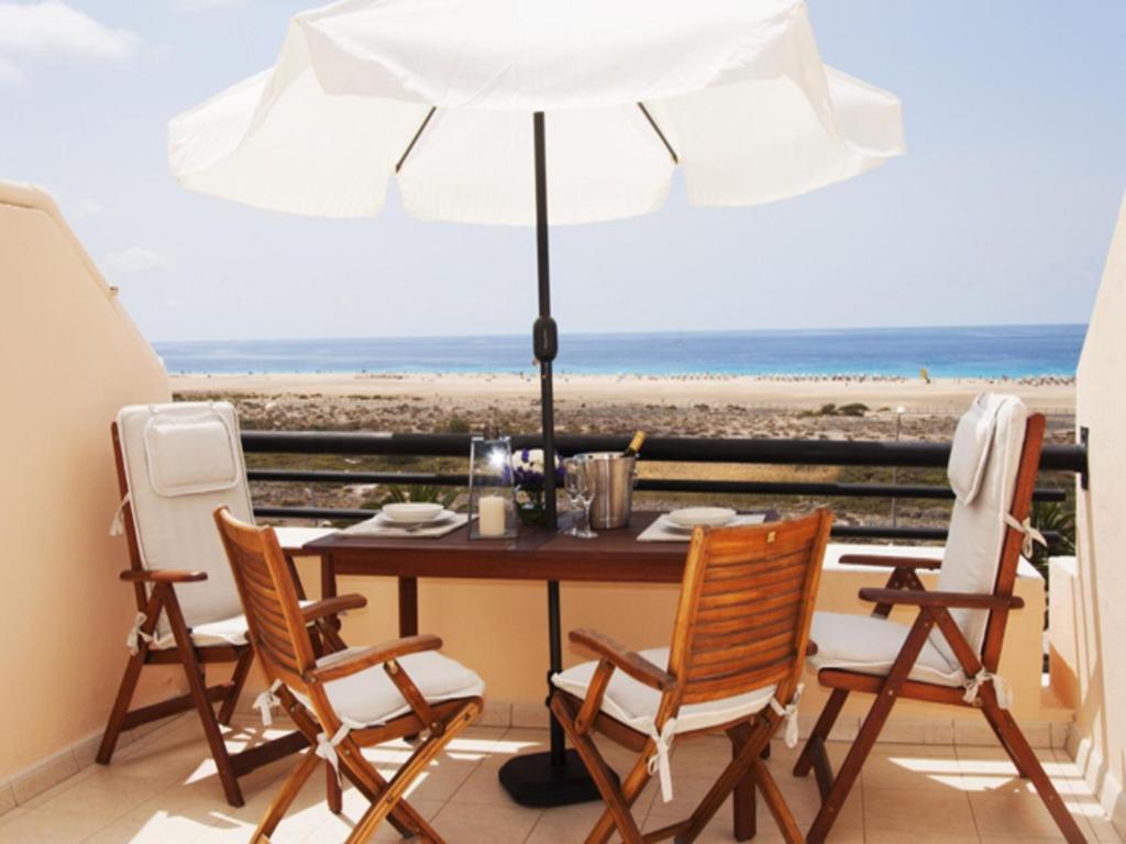 モロ・デル・ハブレにあるSeaviews Morro Jable by VillaGranCanariaのビーチ用のテーブル(椅子付)とパラソル付