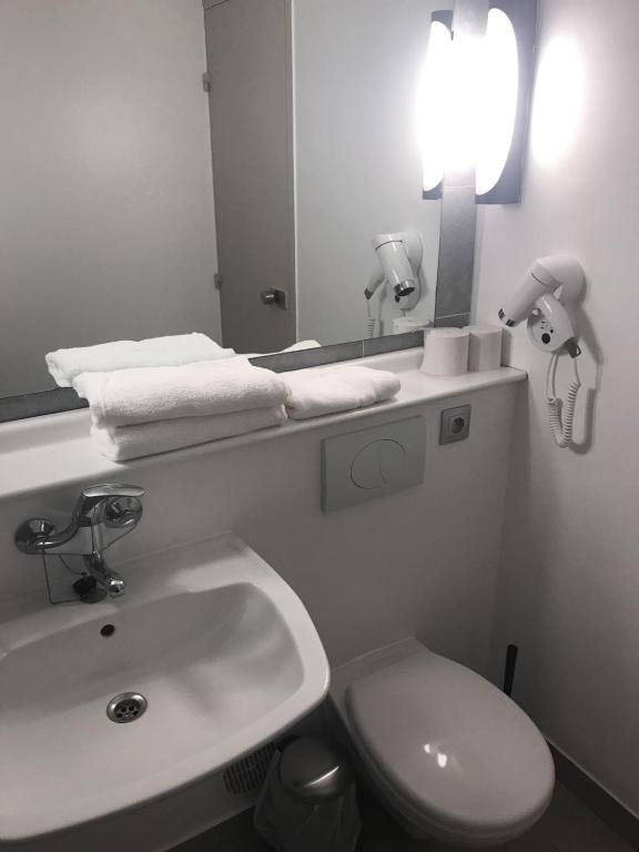 a bathroom with a sink and a toilet and a mirror at Kyriad Cambrai in Cambrai