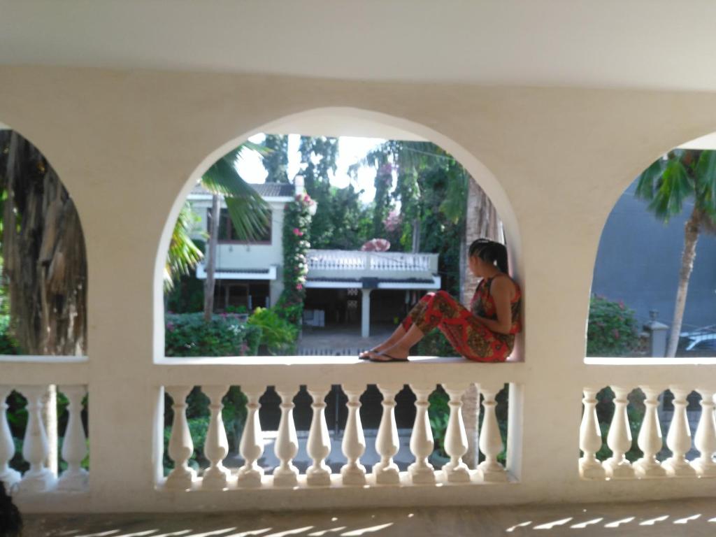 een vrouw die op een balkon zit en uit het raam kijkt bij Akogo House - Hostel and Backpackers in Mombasa