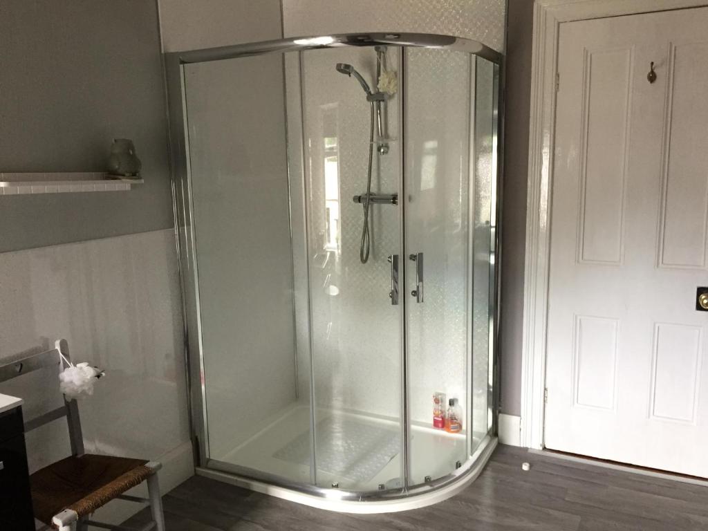 a shower with a glass door in a bathroom at Gardenvale Manor House B&B in Stranocum