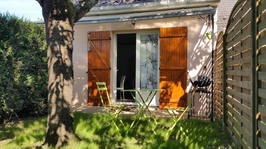 una casa con puertas de madera, una mesa y un árbol en Le Mas des Loups, en Arpajon