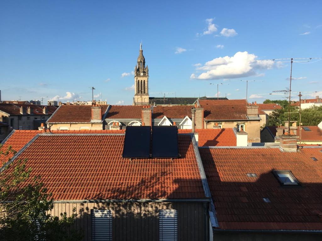 une vue sur les toits avec une tour d'horloge en arrière-plan dans l'établissement L'Atelier Victoria -Mon Desert & Parc St Marie -55m2, à Nancy