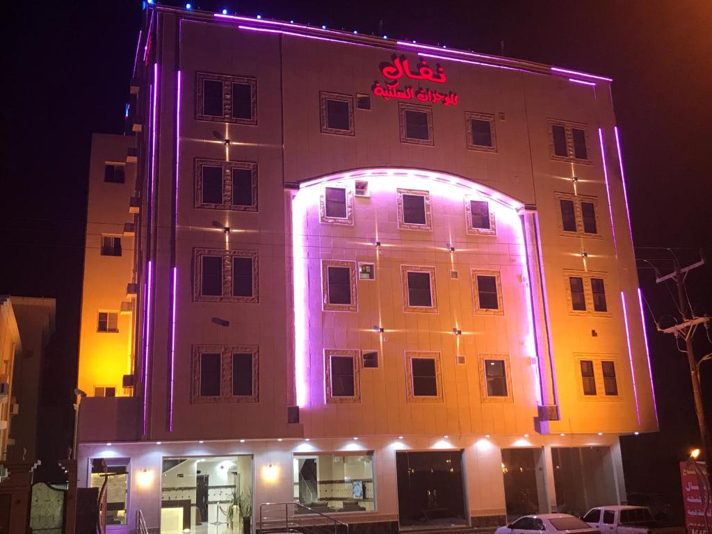 un edificio con luces púrpuras en el lateral. en Nafal Hotel Suites, en Qal'at Bishah