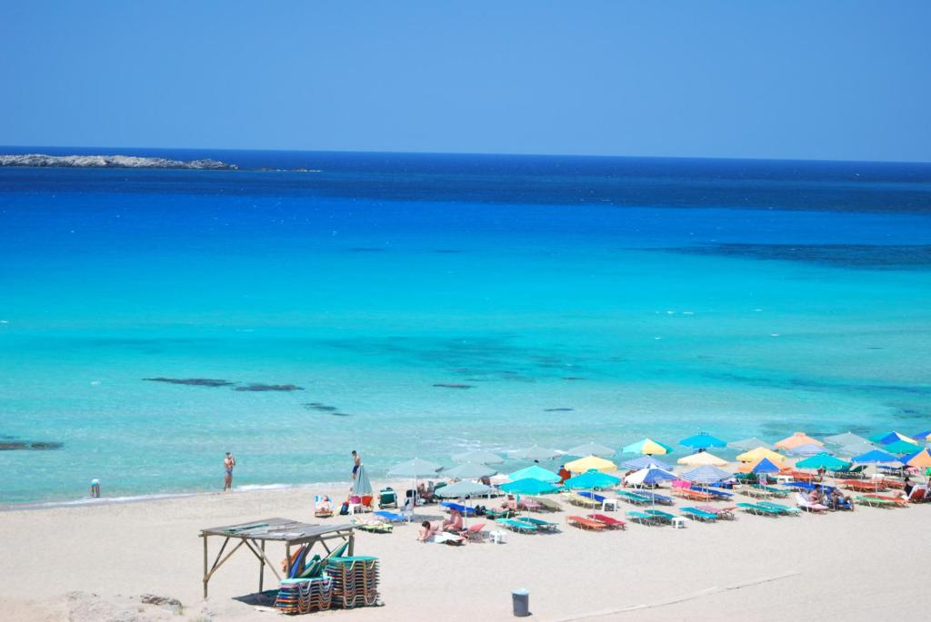 a beach with umbrellas and people on the beach at Romantica Apartments in Falasarna