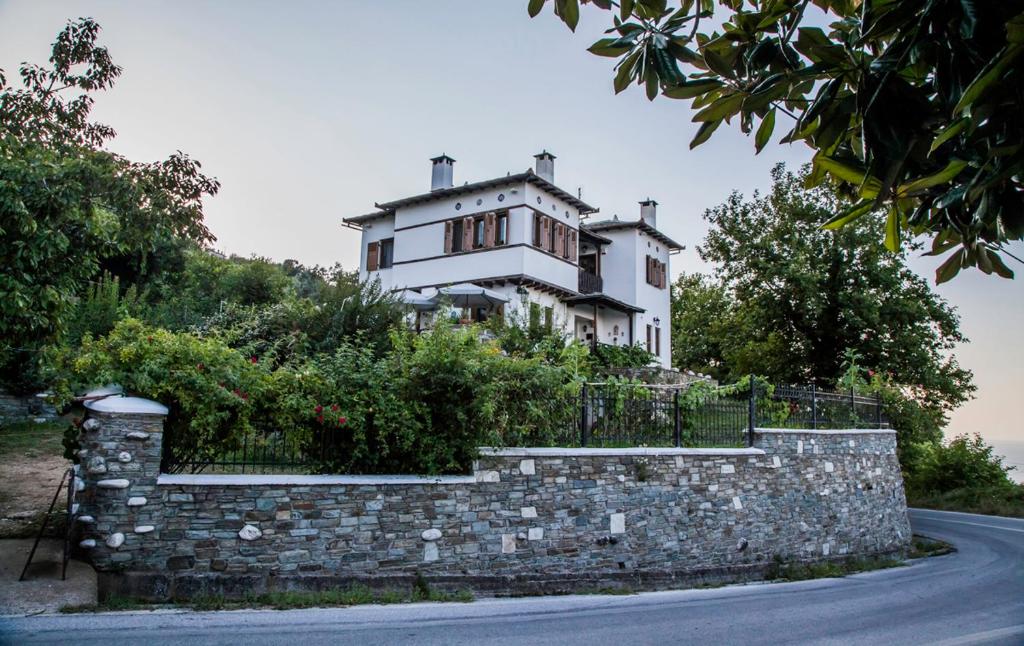uma casa numa colina com uma parede de pedra em Pension Panos em Agios Dimitrios