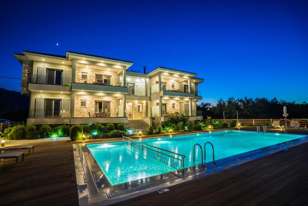 una gran mansión con piscina por la noche en Zante Suites, en Alikanas