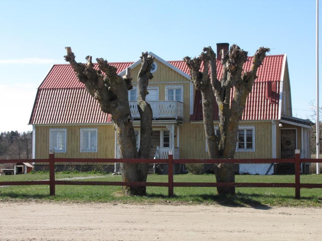 two trees in front of a house with a fence at Stålemara Gård Krickan in Fågelmara