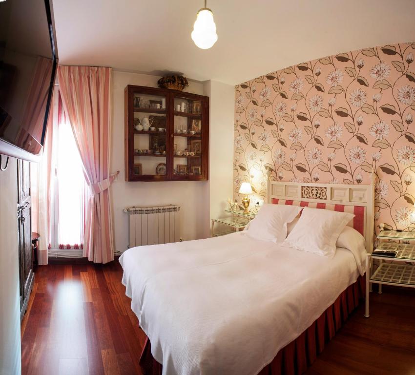 una camera da letto con un grande letto bianco con una parete di Ch Hostal Victoria a Cuenca