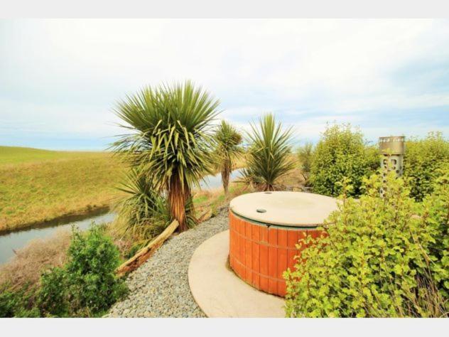 an orange tank sitting next to a river with palm trees at Old Bones Lodge in Oamaru