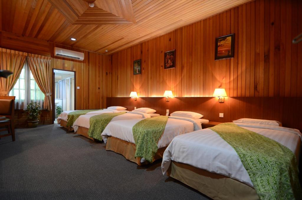 a row of four beds in a room with wooden walls at Eastwood Valley Golf & Country Club in Miri