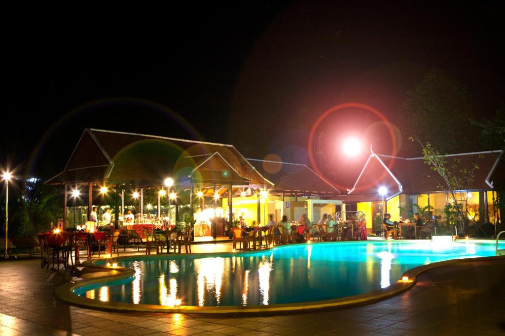 a swimming pool at night with people sitting around it at Don Bosco Hotel School in Sihanoukville