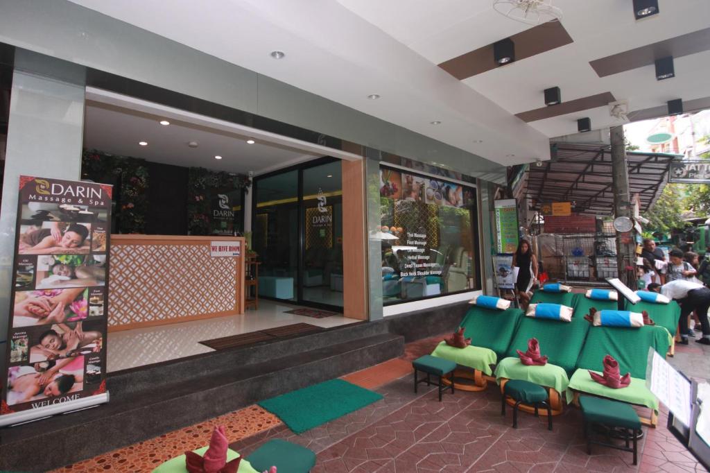 a store with green chairs and people walking in front of it at Darin Hostel in Bangkok