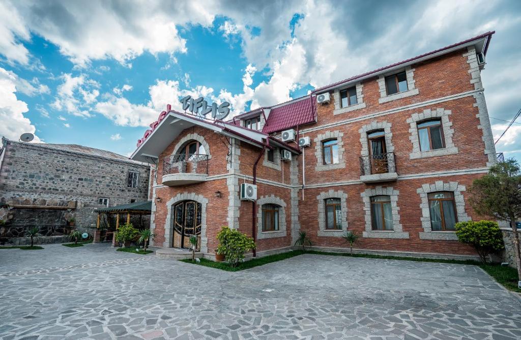 a large brick building with a parking lot at Hotel Tiflis in Akhaltsikhe