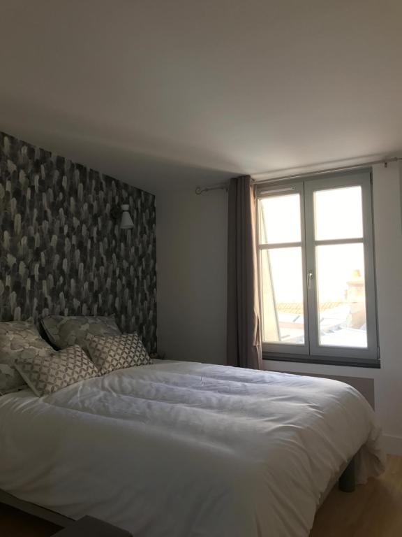 - une chambre avec un grand lit blanc et une fenêtre dans l'établissement F2 STANISLAS, à Nancy