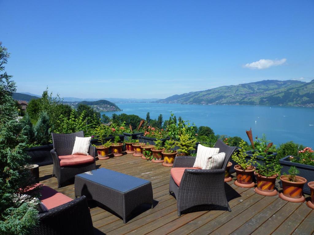 una terrazza con sedie, tavoli e vista sull'acqua di B&B Haussener a Krattigen