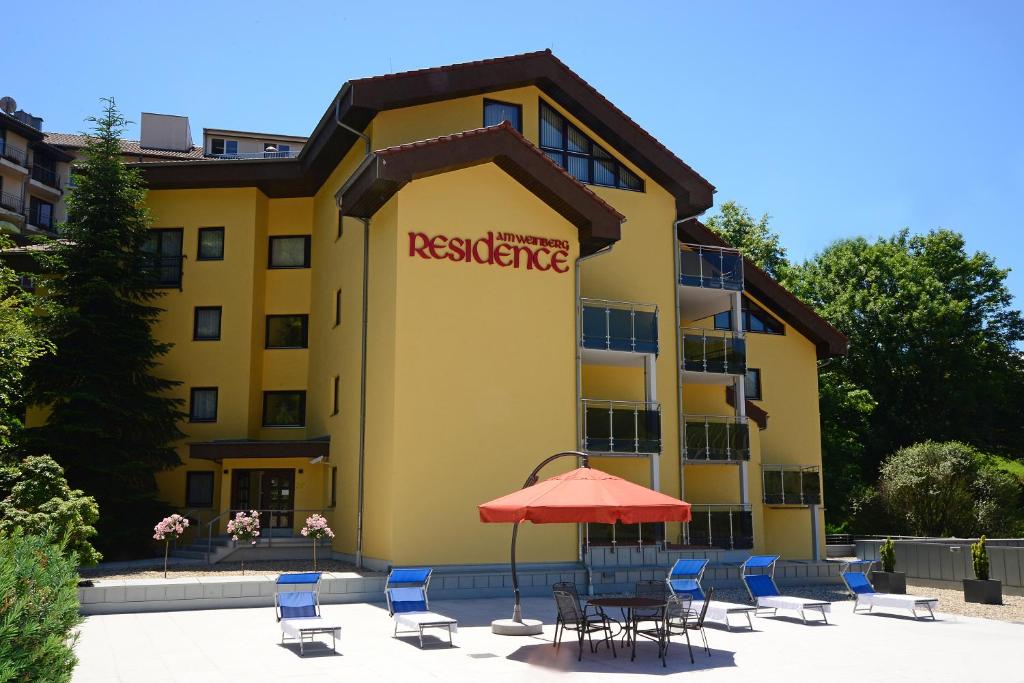 ein Hotel mit Stühlen und einem Sonnenschirm davor in der Unterkunft Residence am Weinberg / Travellers Hotelbetriebs GmbH in Sasbachwalden