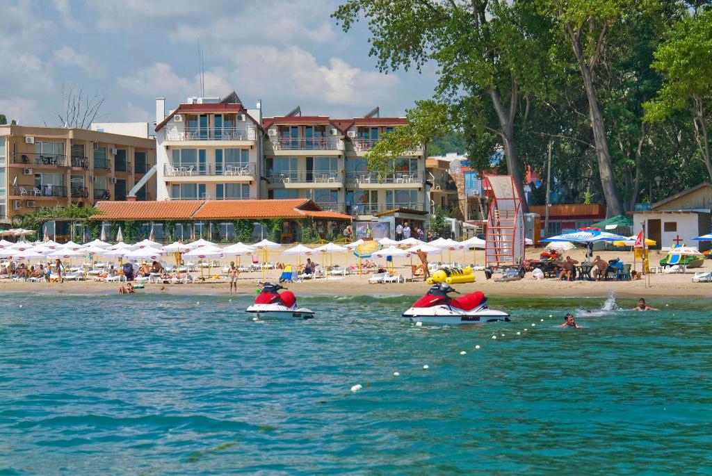 two people are riding on boats in the water on a beach at Свети Никола Каваците in Sozopol