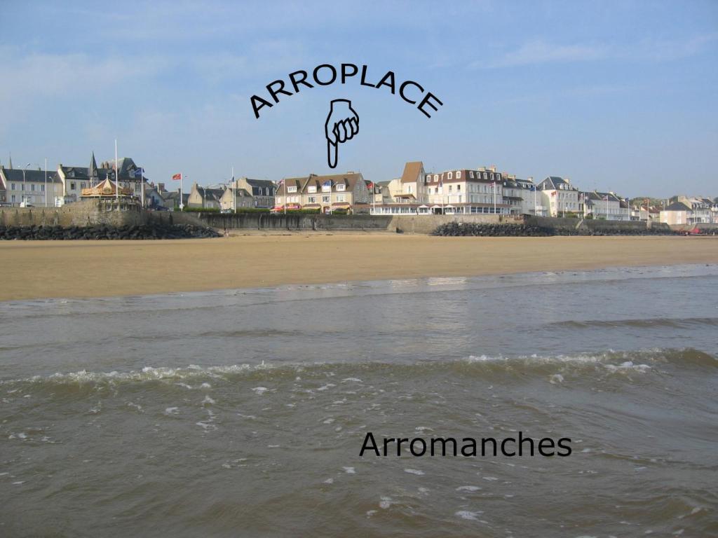 a kite flying over the ocean next to a beach at Arroplace in Arromanches-les-Bains