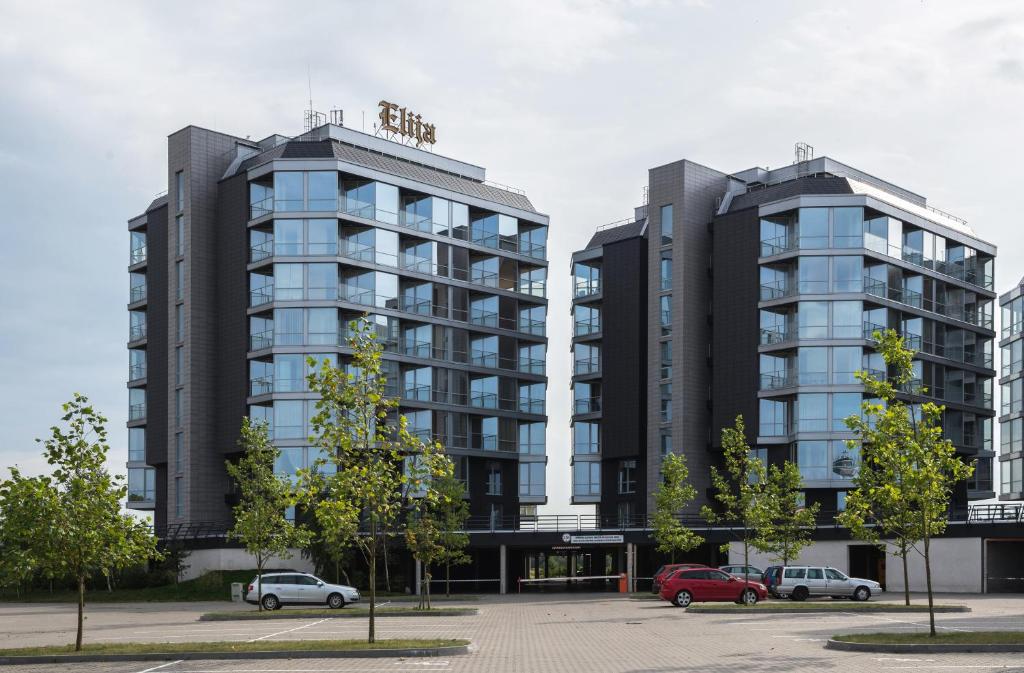 dos edificios altos con autos estacionados en un estacionamiento en Elijos apartamentai, en Šventoji