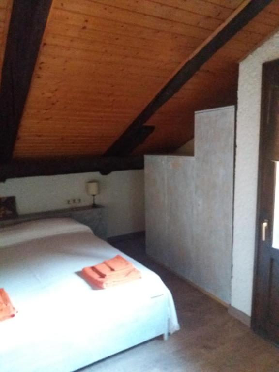 um quarto com uma cama branca e um tecto de madeira em Maso del Capitel em Commezzadura