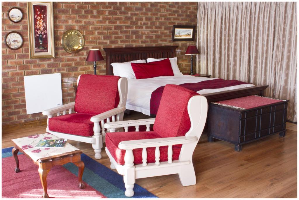 Asante Guest House في فاندربيجلبارك: غرفة نوم بسرير وكرسيين وطاولة