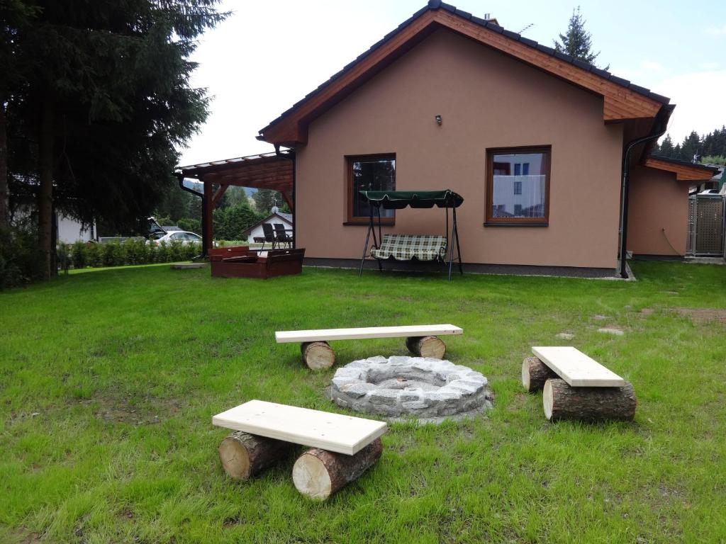 a group of picnic tables in the grass in front of a house at Moderni Domek Lipno in Lipno nad Vltavou