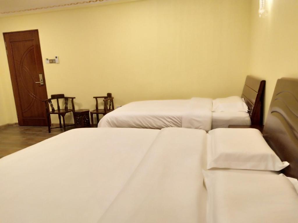 two beds in a room with white sheets at Uncle Ho Motel in Papar