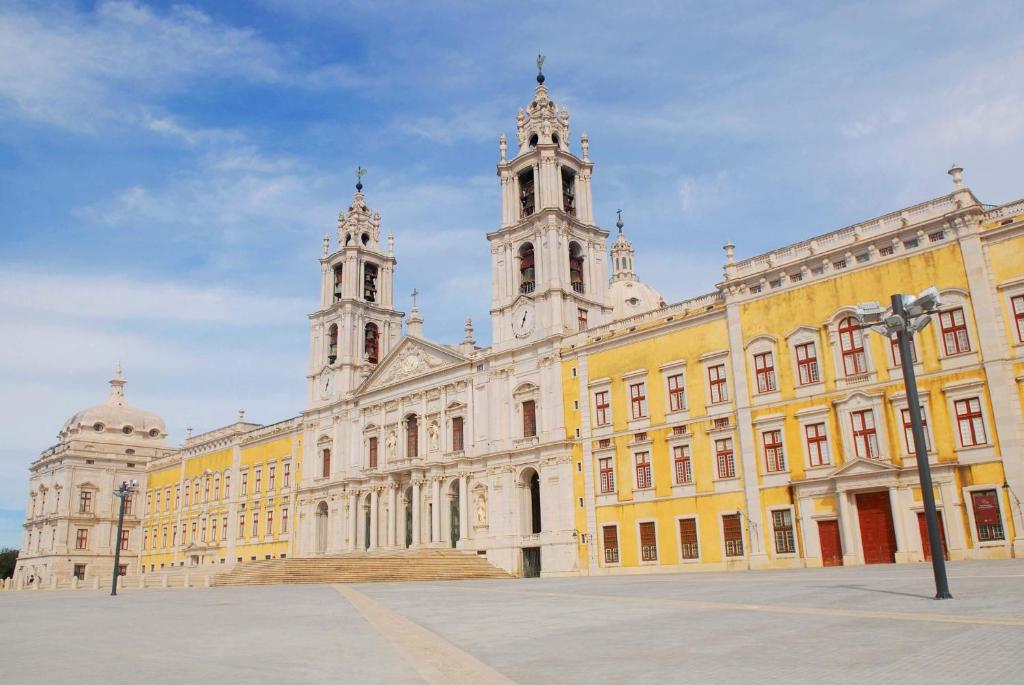 a large yellow building with a clock tower on it at Ericeira Surf and Sun in Ericeira