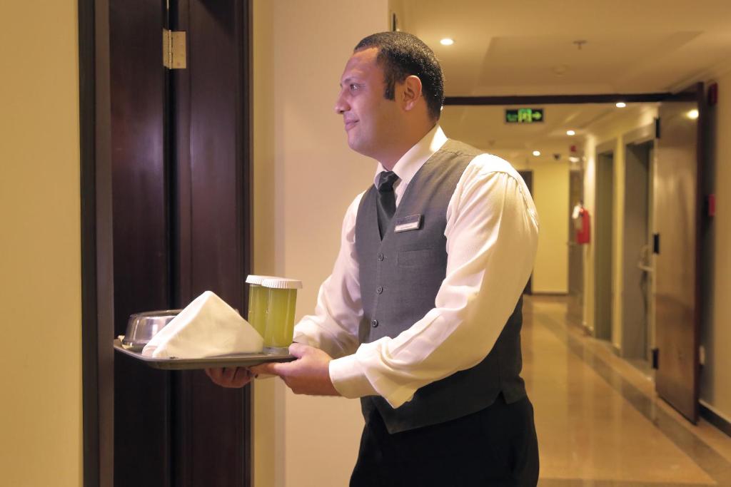 a man holding a tray of food and a drink at Saja Al Madinah in Al Madinah