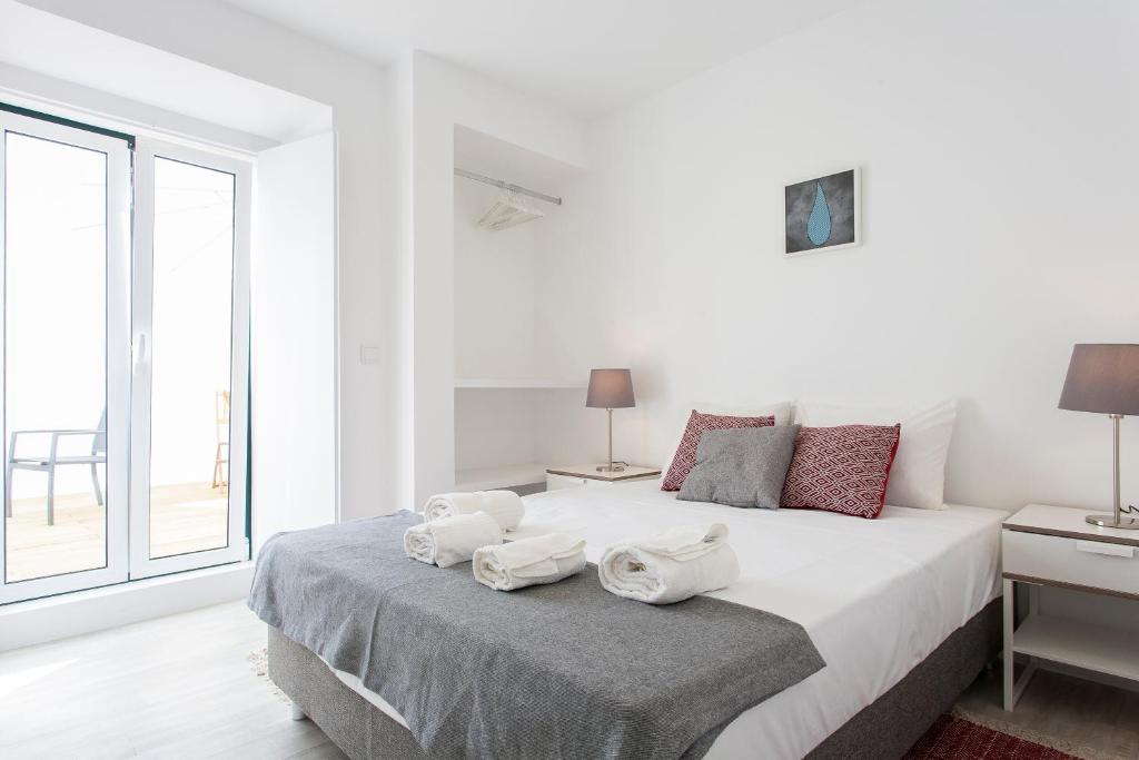 um quarto branco com uma cama grande e toalhas em Castelo Picão Apartments em Lisboa