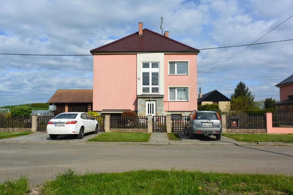 różowy dom z dwoma samochodami zaparkowanymi przed nim w obiekcie Rodinné ubytování - Family accommodation w mieście Kobylice