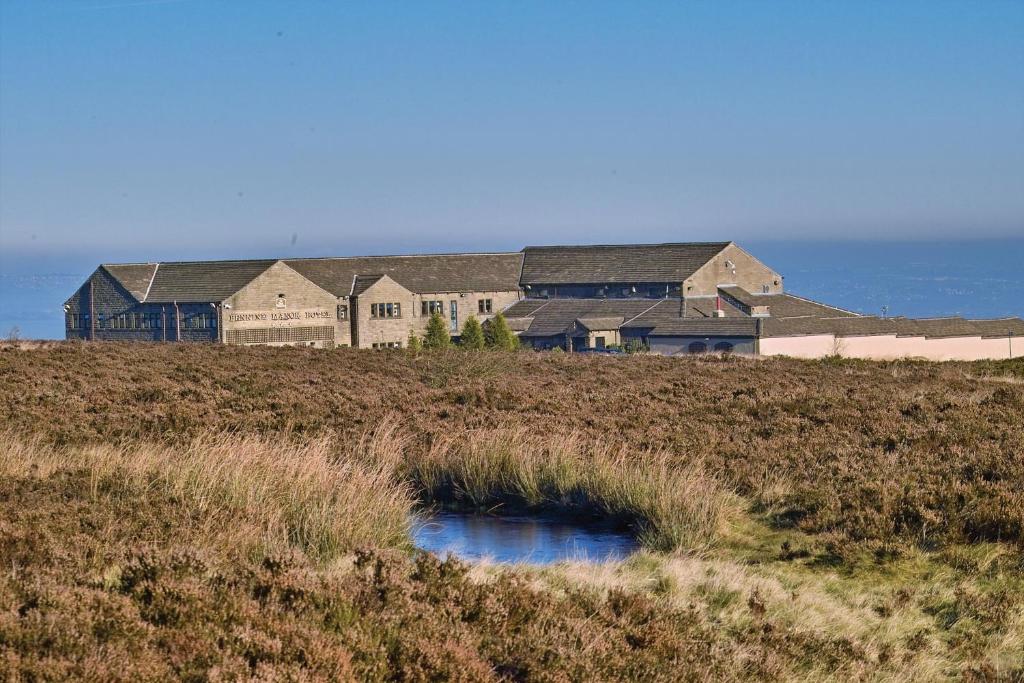 a large house on top of a grassy hill at Pennine Manor Hotel in Huddersfield